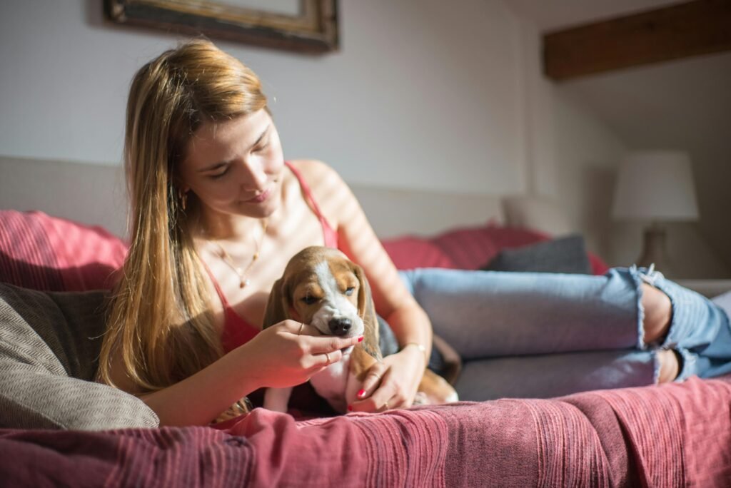 A young woman lounging indoors with her beagle puppy, enjoying a peaceful moment.